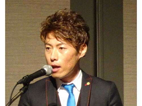 あいさつする高松社長と「ブルーコンシャスグループ総決起集会」会場の様子（写真下）
